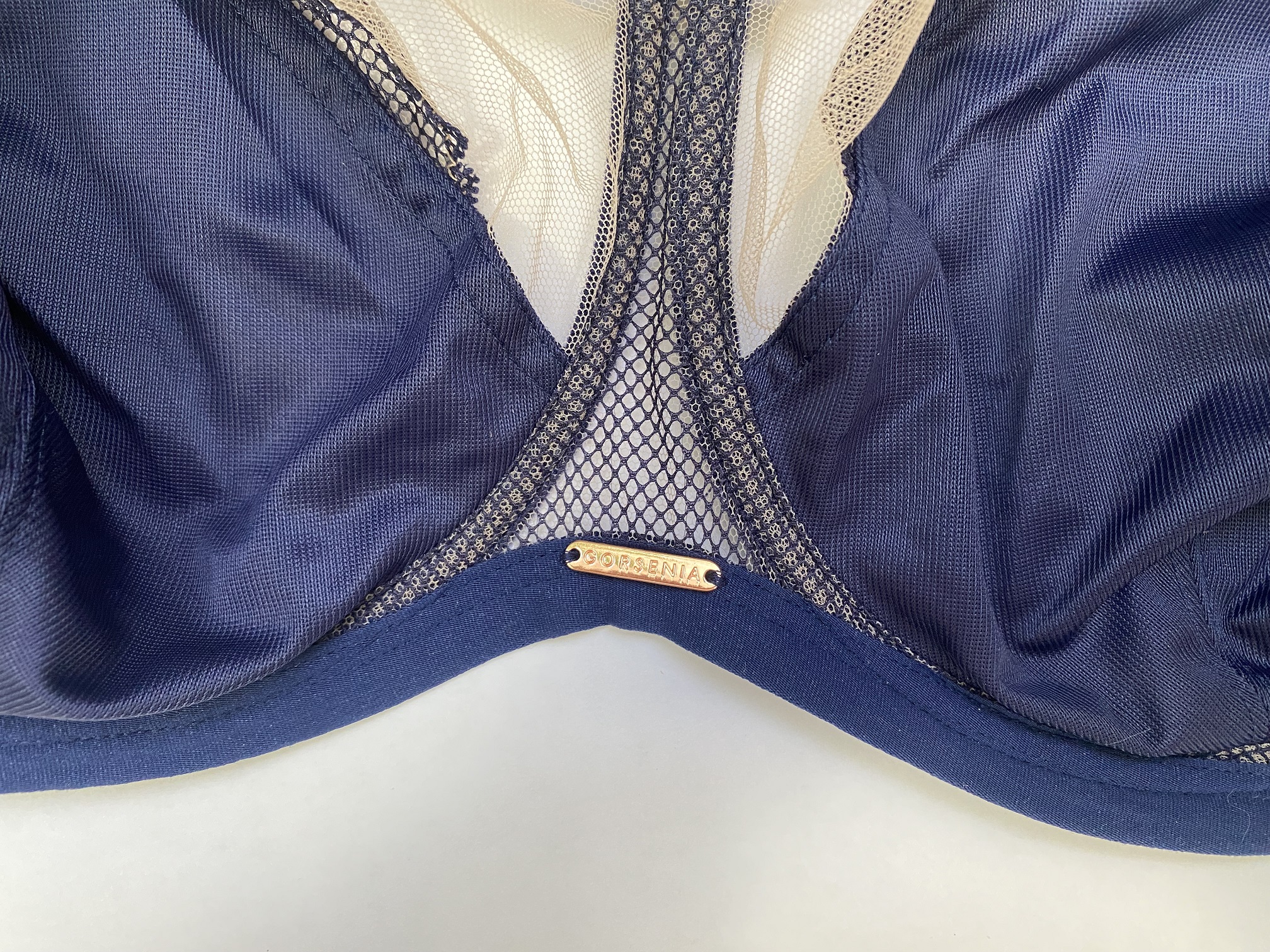 Золотистое украшение с надписью GORSENIA на ластвице между чашками бюстгальтера